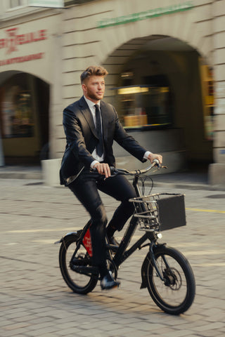 Junger Mann im Anzug und Krawatte auf dem Fahrrad