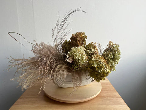 Thanksgiving arrangement dinner table centerpiece dried local flowers hydrangea miscanthus grass elegant minimalist trough style ceramic vase foam free sustainable eco friendly