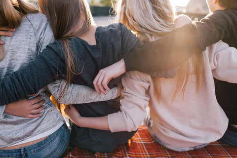 Group of friends sitting together on a blanket, showcasing healthy living and the importance of relationships for well-being