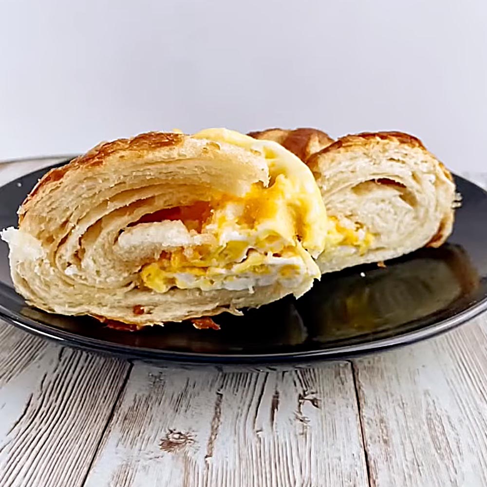 Croissant with egg on a black plate