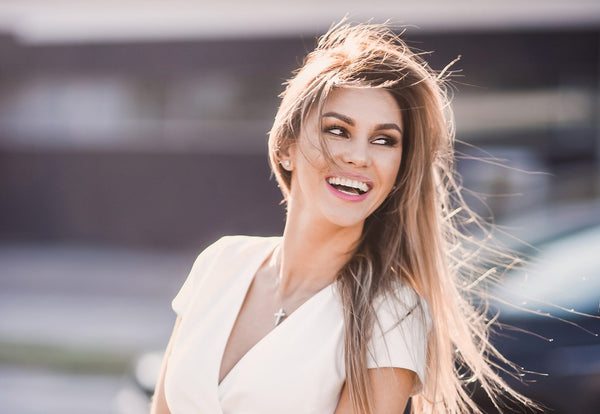 Smiling woman in a white dress standing outside