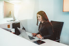 Receptionist typing on computer and answering emails