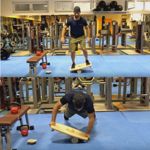 Athletic man on a balance board, standing on top, lying down in plank position.