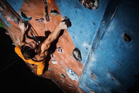 Muskulöser Mann beim Klettern an einer Indoor Kletterwand