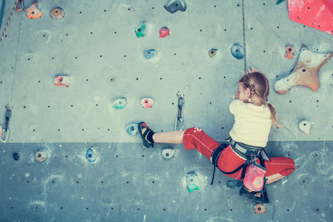 Kleines Mädchen klettert an einer Indoor Kletterwand