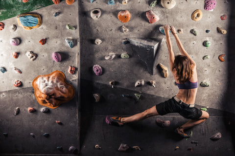 Junge Frau übt das Klettern an einer Indoor Felswand