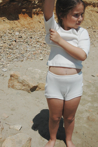 brown hair girl in white suit on rocky beach