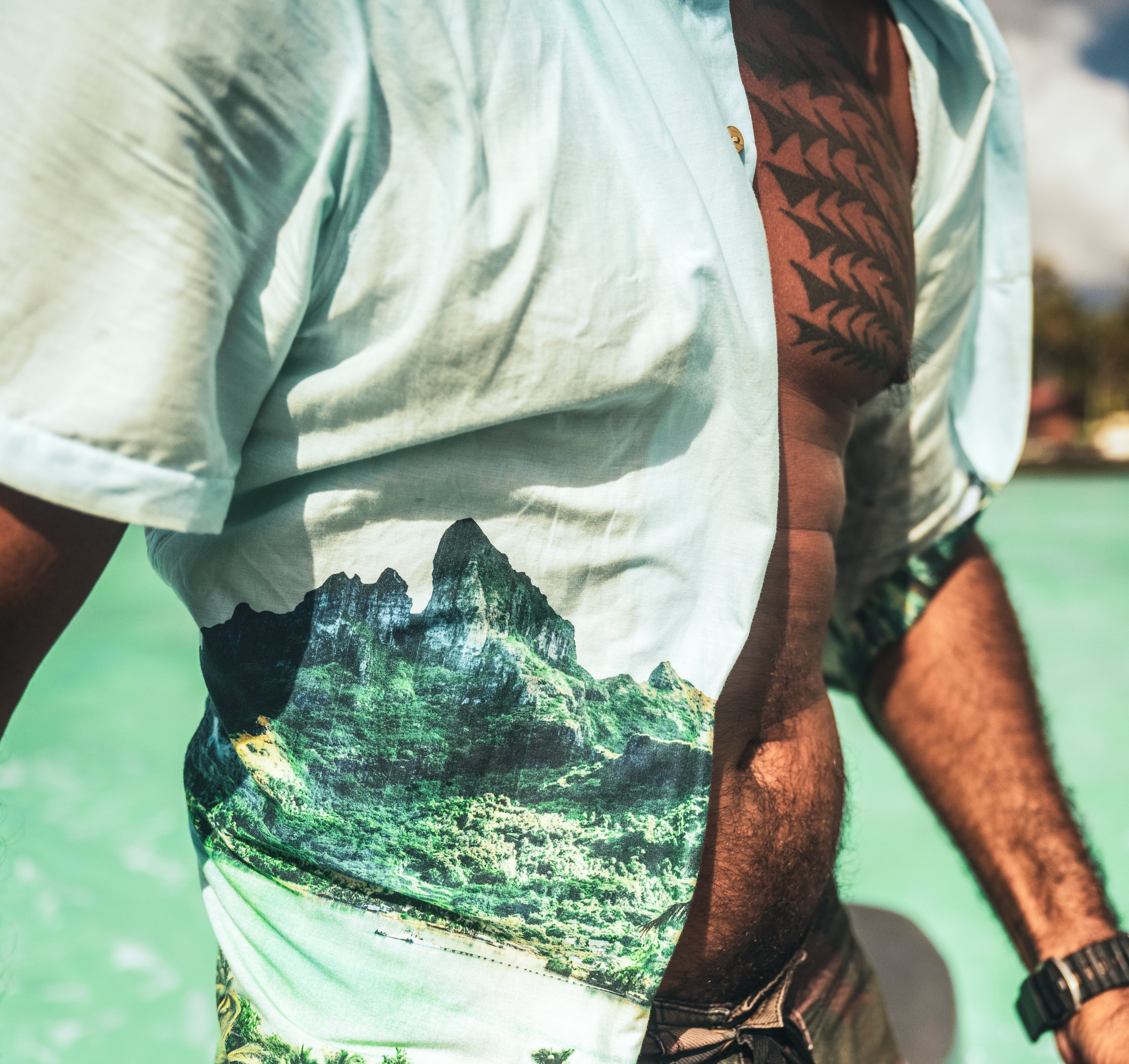 Man in Tahiti, wearing the unbuttoned Roark Gonzo Camp Collar Shirt - Hinano Otemanu Light Blue, immersed in the azure waters, embodying the carefree island lifestyle.
