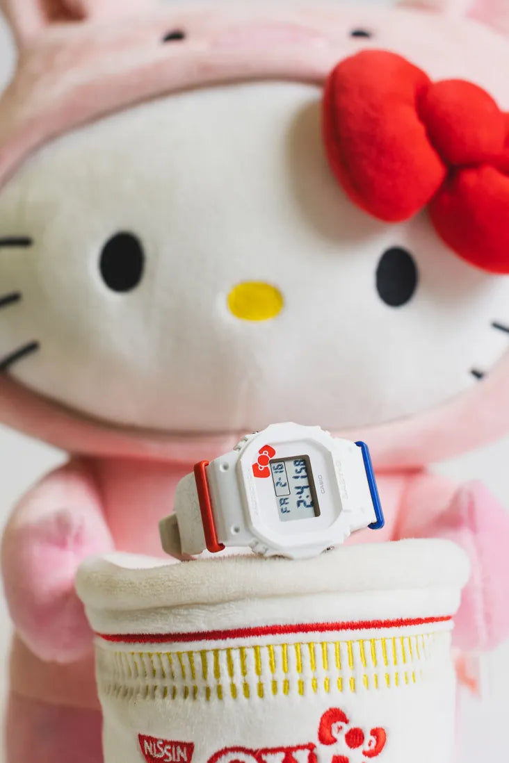 Hello Kitty plush holding a Baby-G x Hello Kitty 50th Anniversary digital watch, showcasing a playful and nostalgic collaboration.