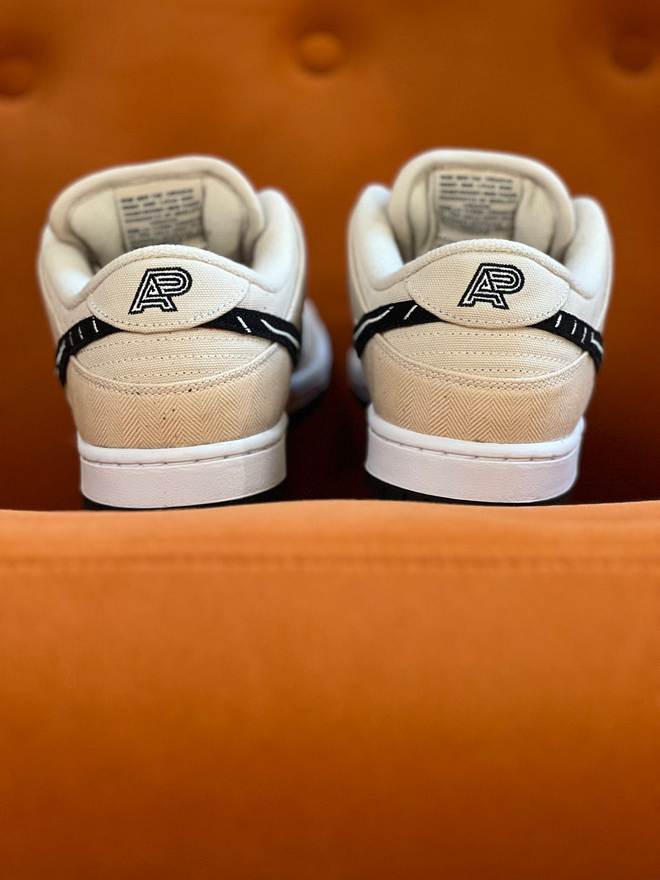 Image of the back heels of the Nike SB A&P Dunk Low sitting on an orange couch