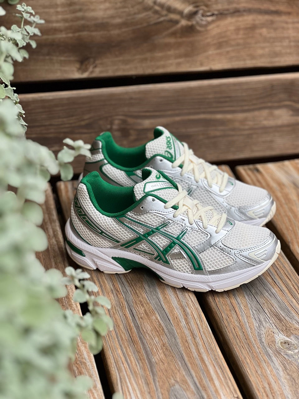 Image of the ASICS GEL-1130 together on a wooded bench with a green leafy background.