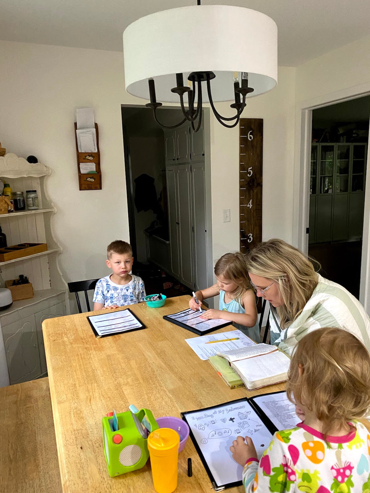 woman and kids reading around a dining table in pajamas and blankets