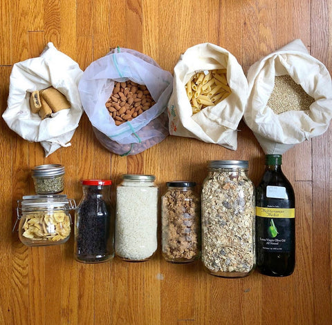 This image shows bulk food items such as pasta, grains, granola, and olive oil packaged in reusable bags, jars, and bottles.