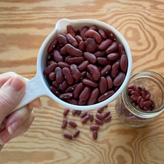 Dried red kidney beans pictured in a white measuring cup