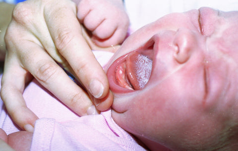 Infant a white tongue and a natal tooth