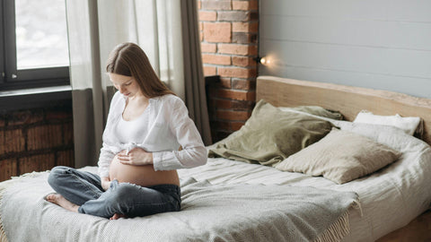 prenant woman sitting on the bed