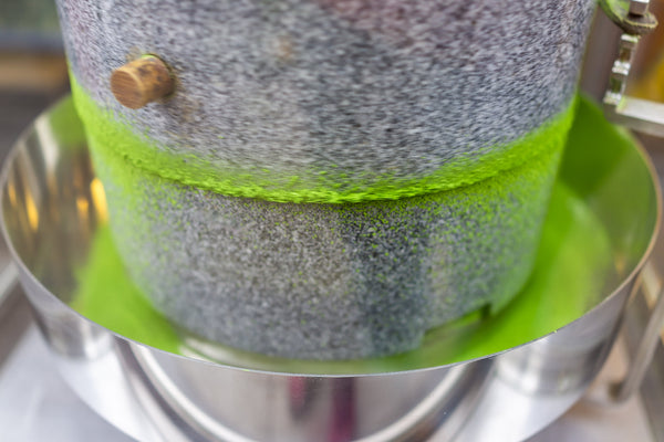 Matcha grüne Tee-Schleifsteinmaschine in Bewegung mit lebendigem bunten Pulver Nahaufnahme in Fabrik