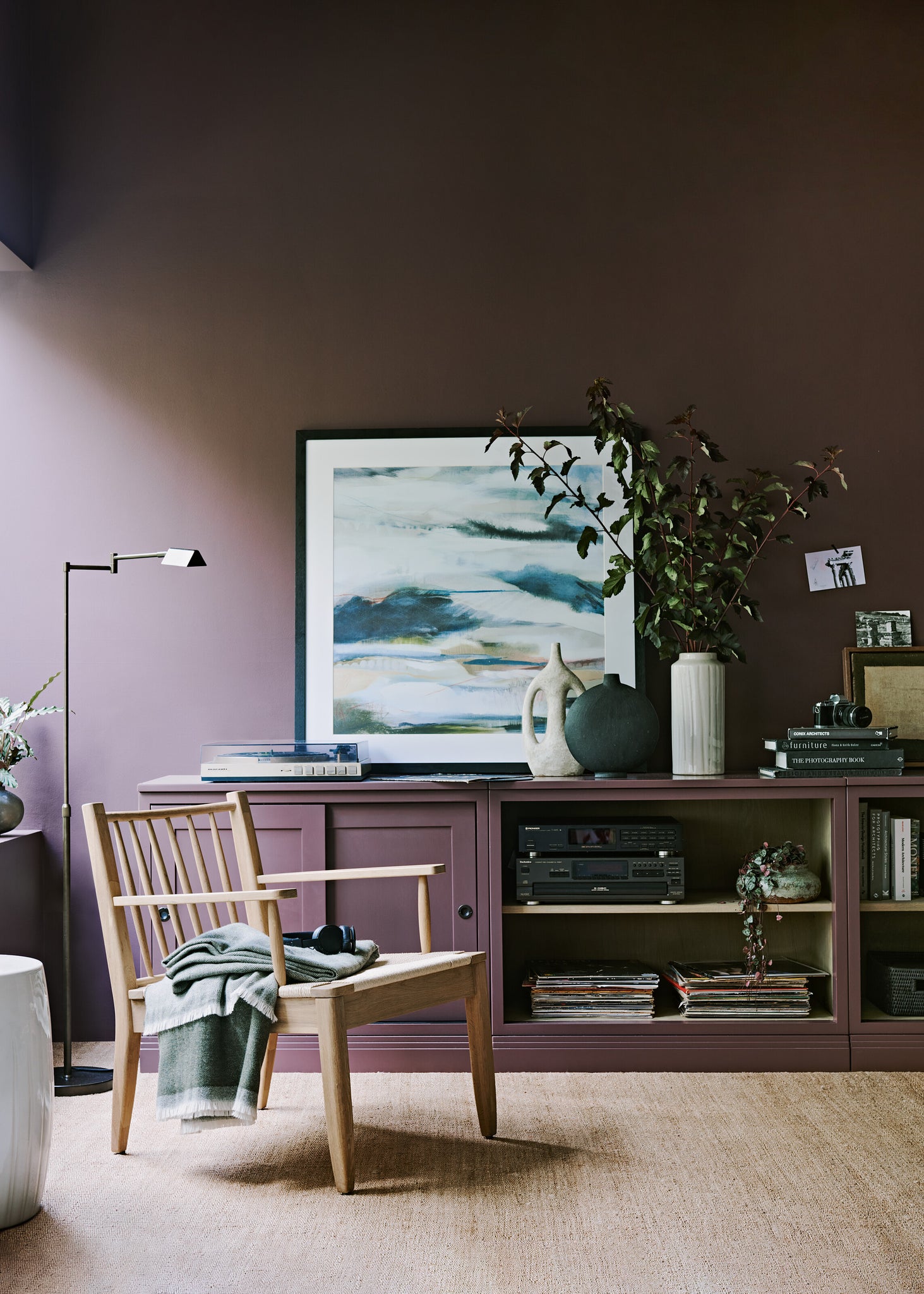 deep purple coloured wall with empty wooden arm chair in shot