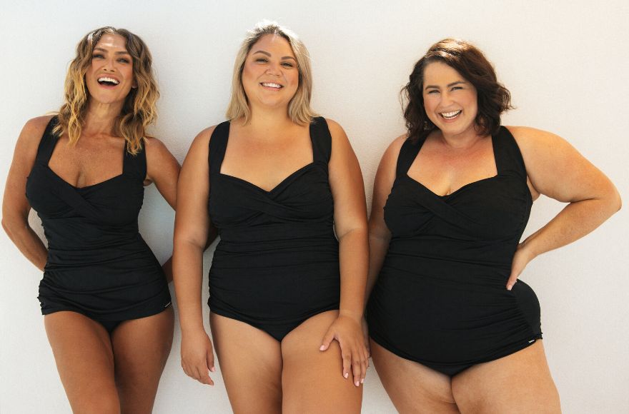 3 women with different body shapes and sizes wear the same style of black one piece swimsuit