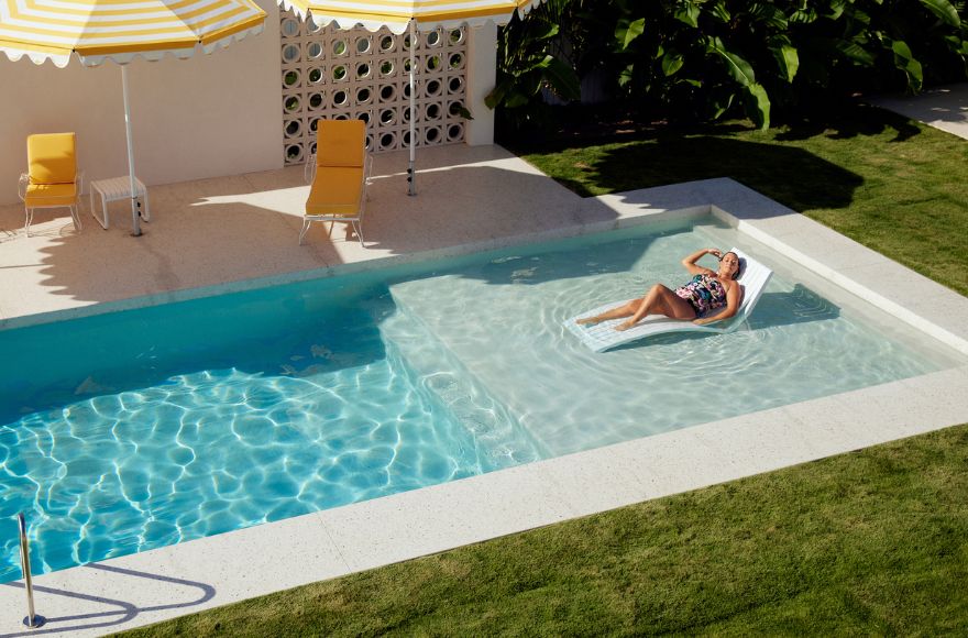 Woman reclines on sun lounger in a Slim Aarons inspired pool