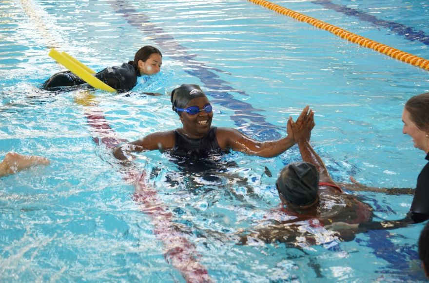 4 women participate in swimming lessons in a public pool