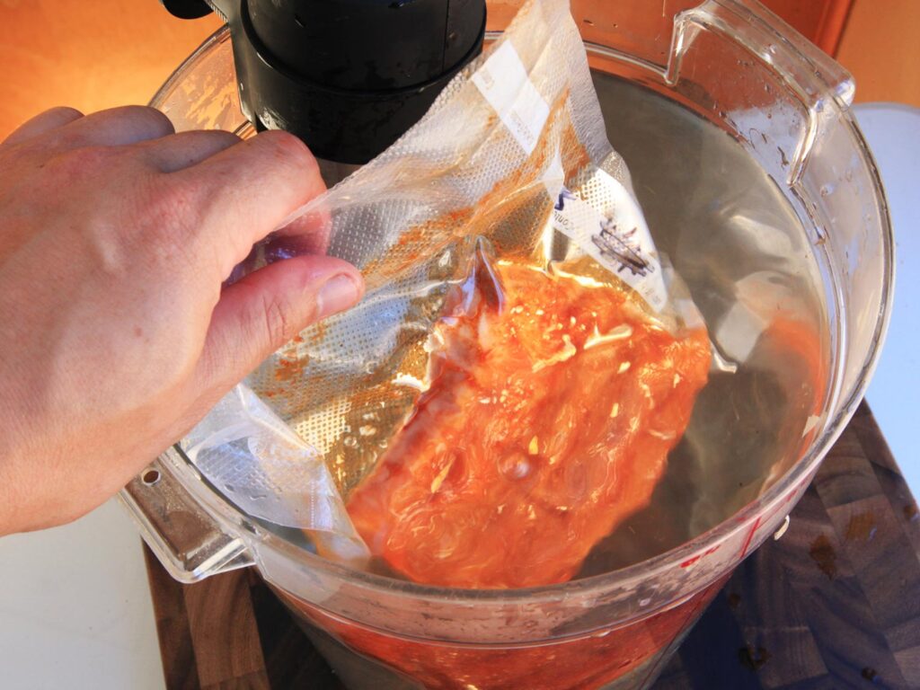 Placing a vacuum-seal bag of marinated ribs in a water bath to cook sous vide