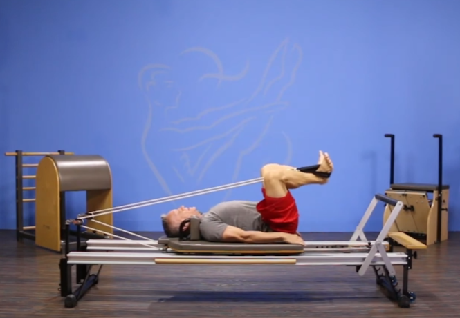 man stretching his back on pilates reformer machine