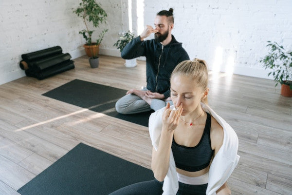 man and woman seated practicing yoga breathing