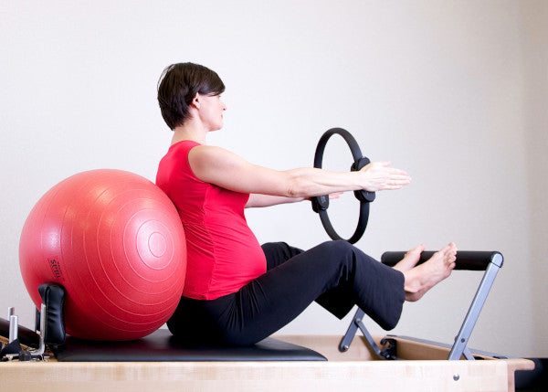 pregnant woman working out on a reformer