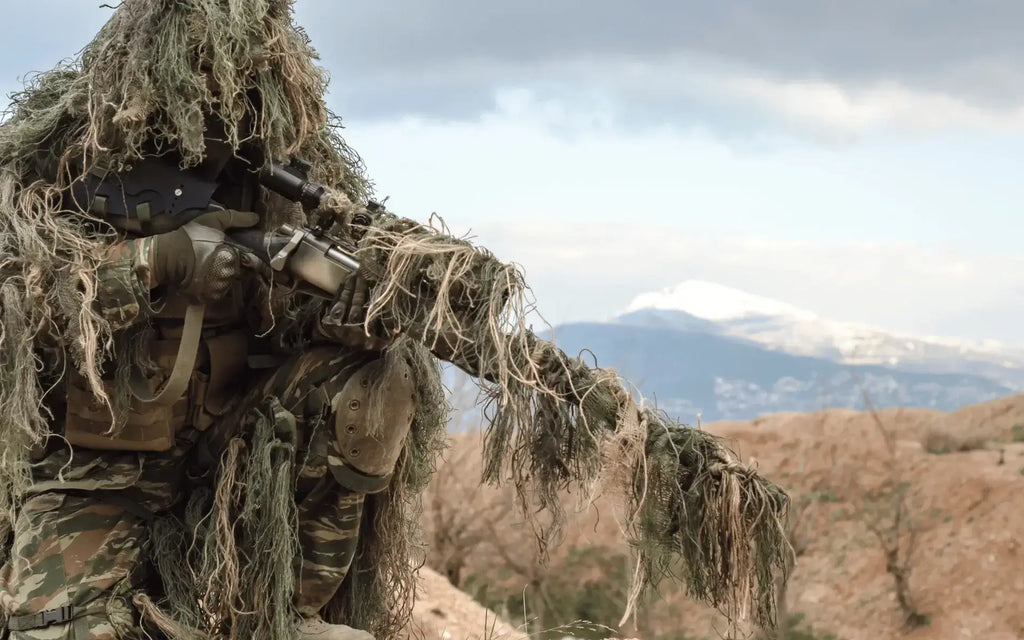 Sniper in ghillie follows in the middle of the countryside to camouflage himself