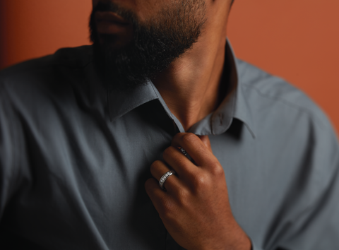 Man holding the center of his button-down shirt and looking left, while showing off his lab-grown diamond ring jewelry