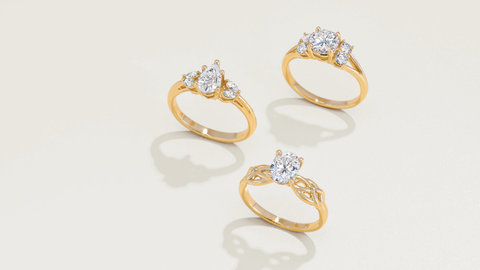 Three different types of yellow gold diamond rings, standing upright on display.