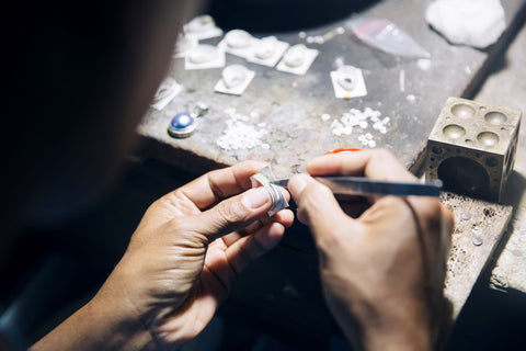 A person trying to restore antique jewelry on their own with their ring and tools in hand.