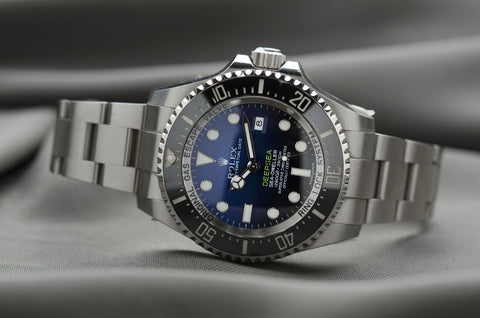 Luxury grey and blue silver Rolex watch laying on it's side on a display