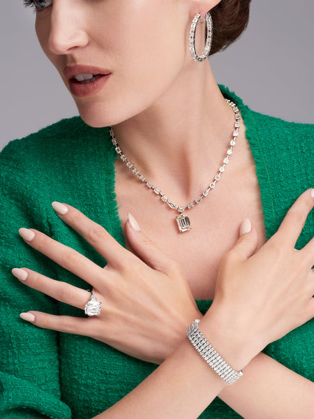 Woman wearing diamond earrings, necklace, bracelet, and ring