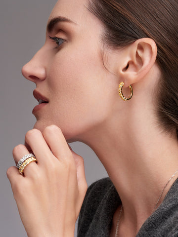 Woman in side profile with earrings and rings