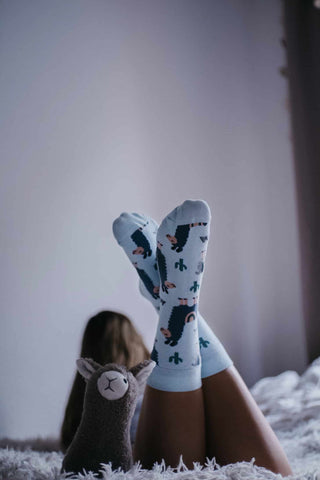 Junges Mädchen mit Lama Alpaka Socken in blau von MYSOX auf dem Bett