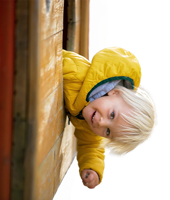 child in yellow jacket playing on daycare equipment