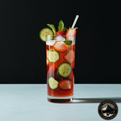   Pimm's Cup cocktail in highball glass with cucumber, strawberry and mint garnishes
