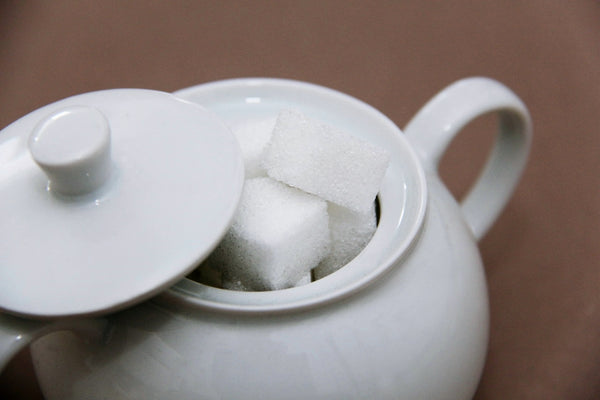 Partially-open white ceramic sugar bowl containing sugar cubes