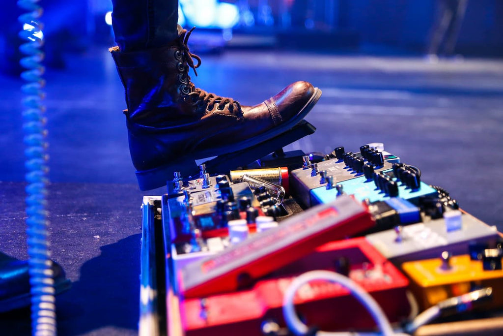 a guitarist stomping his feet to BOSS utility and tuners guitar pedal