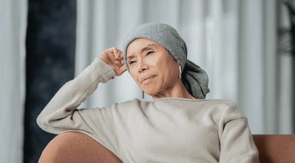 Attractive Asian African American older woman sitting on a couch, smiling with a scully cap on