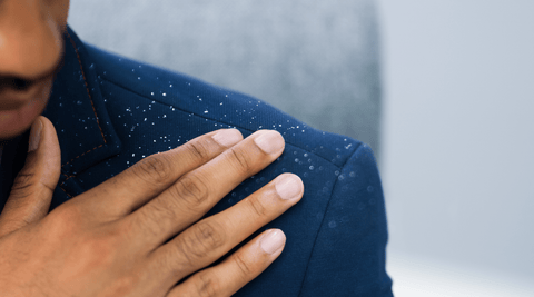 Black man in blue suit brushing dandruff off his shoulder