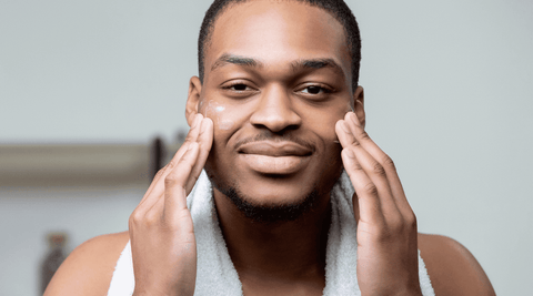 Black man moisturizing his face. 