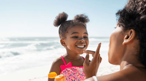 Black woman and child at the beach happy.