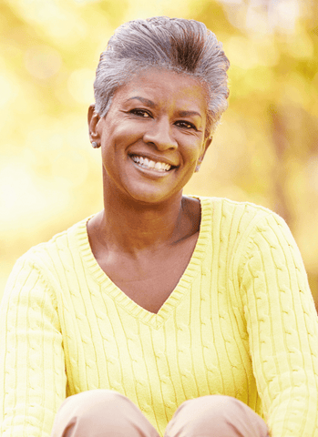 Mature Black Woman Smiling with Anti-Aging Creams and Serums