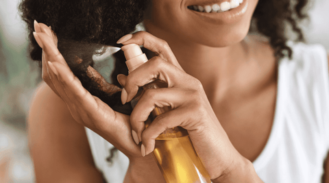 Black woman applying oil in LCO method to her natural hair.