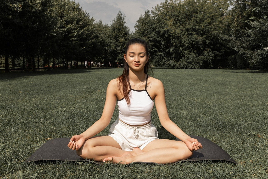 Image of woman sitting on the grass crosslegged meditating