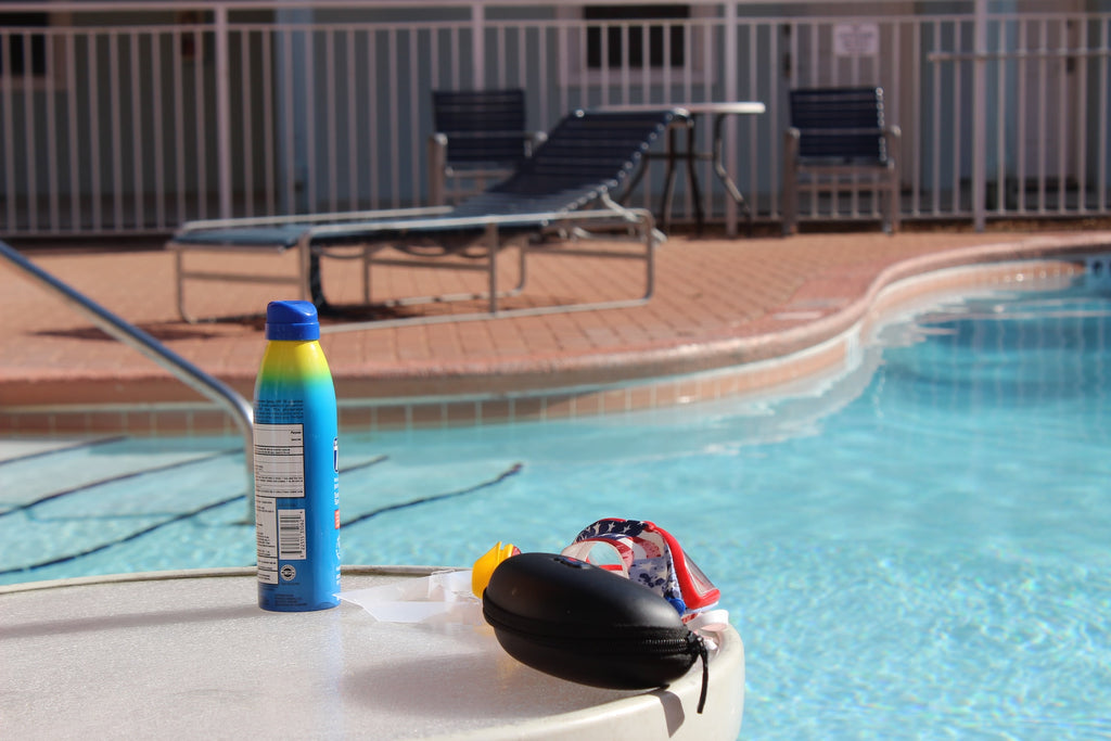 Image of chemical spray aerosol sunscreen next to a swimming pool