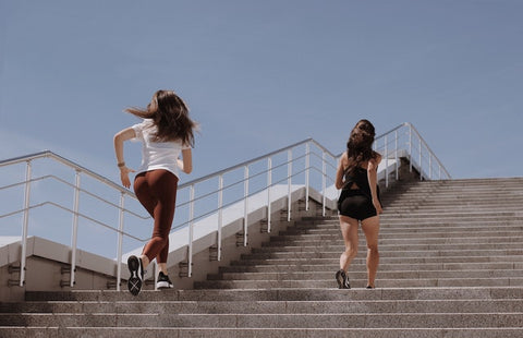 Two woman run up outdoor staircase for exercise